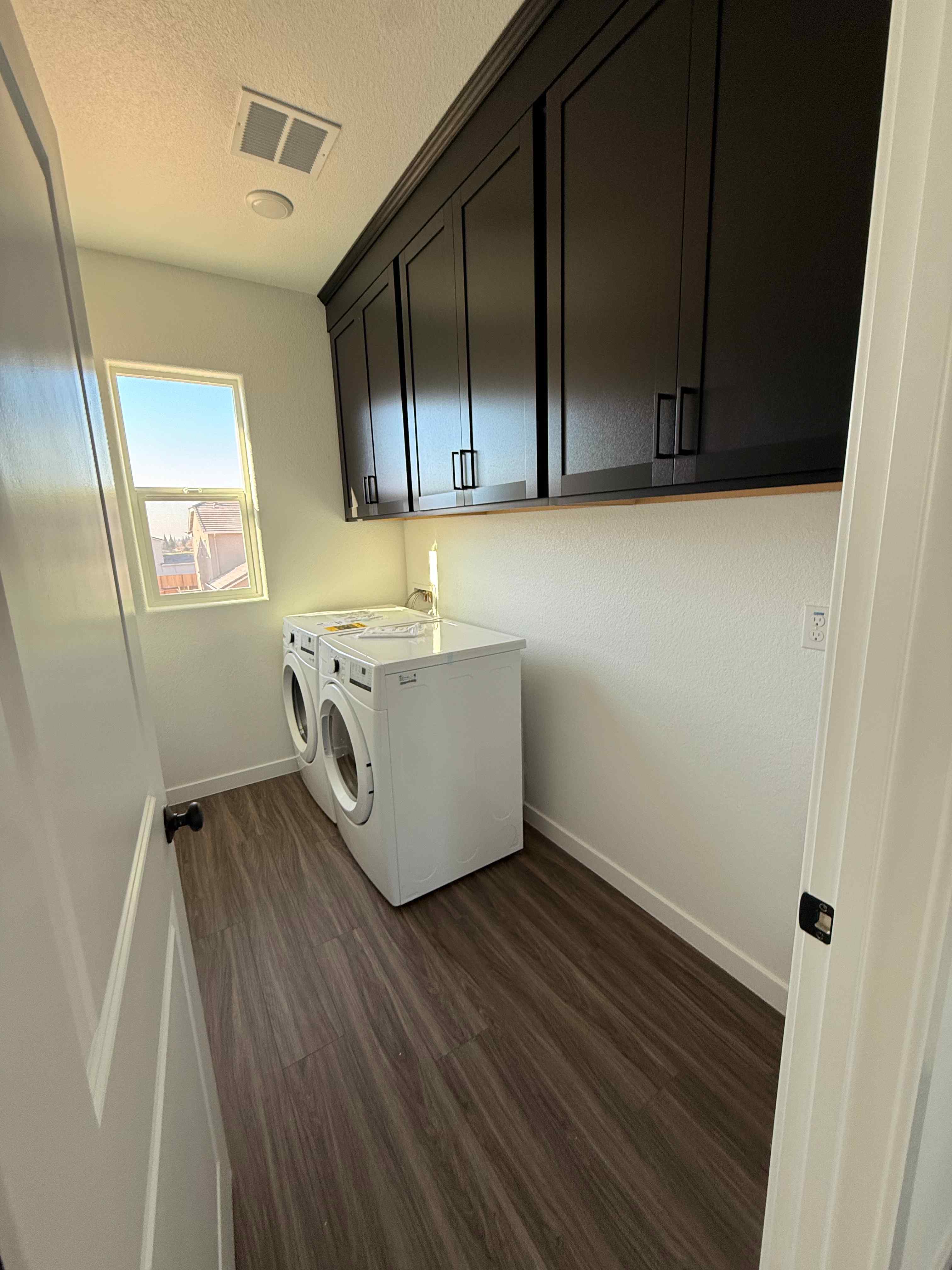 A room with a washing machine and cabinets.