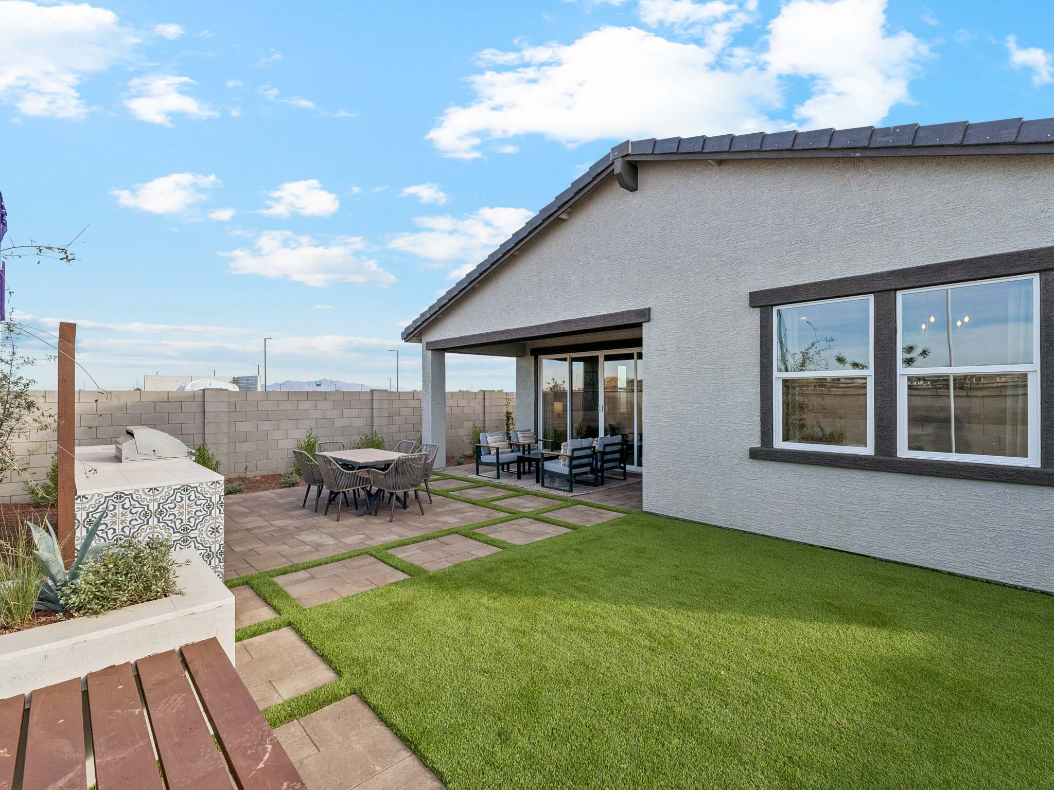 A house with a lawn and a patio with a table and chairs.