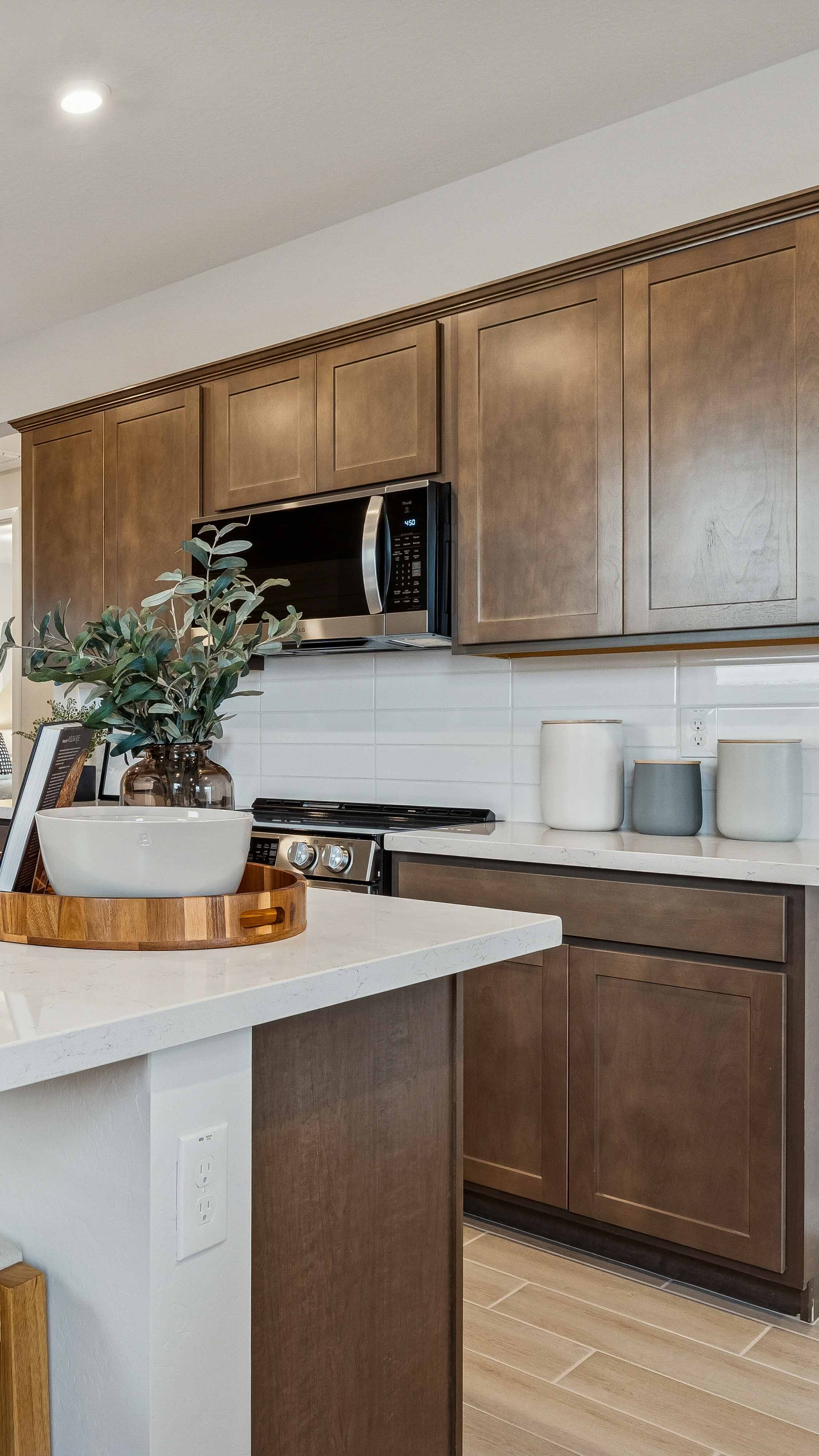 Interior photo of the kitchen island with burlap medium brown cabinets light beige 3cm counters, and light wood-look ceramic tile flooring in the model home Alder floor plan in The Highlands Collection at Skyline Village in San Tan Valley, Arizona by Century Communities New Construction Homes for Sale in Phoenix