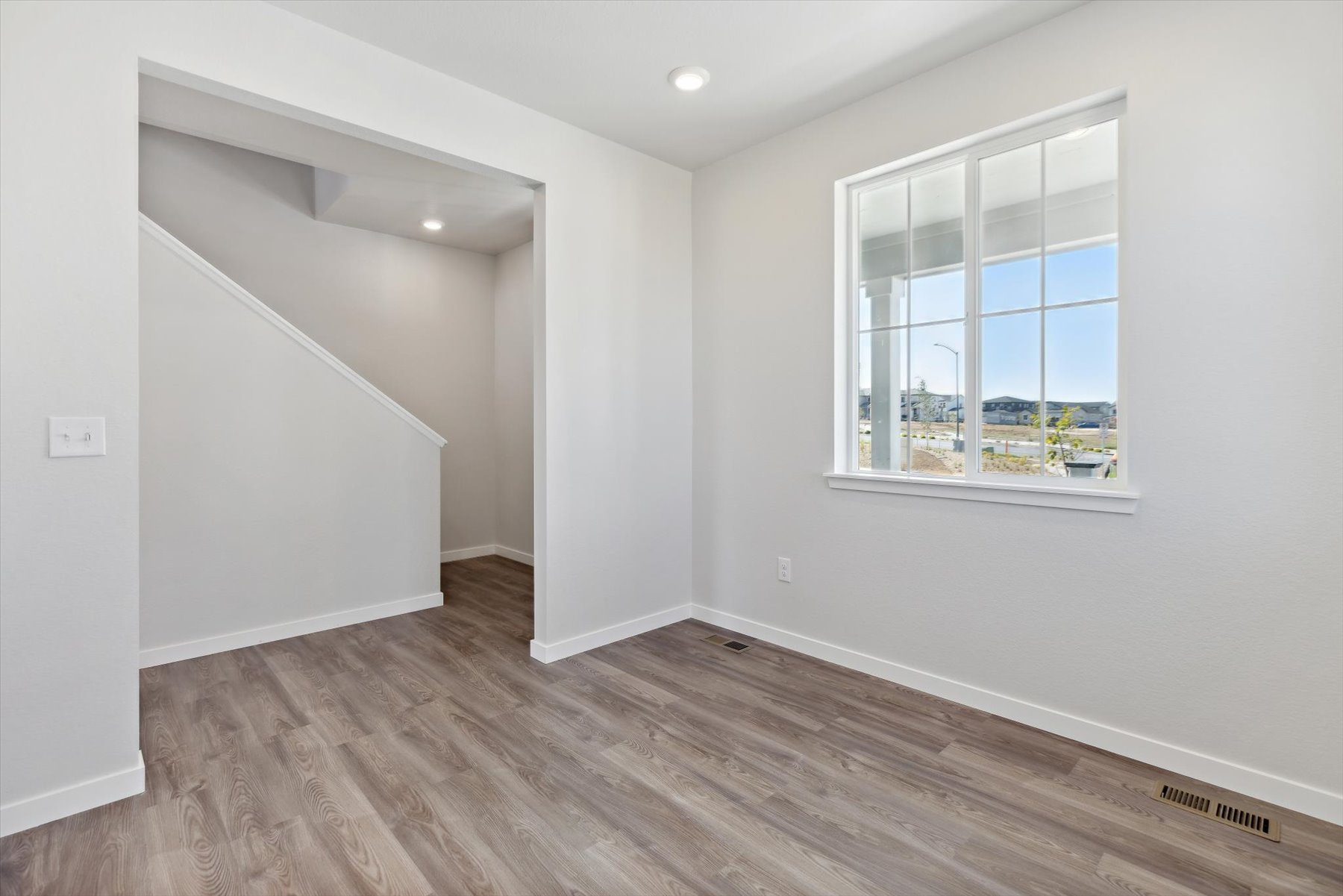 A room with a window and a wood floor.