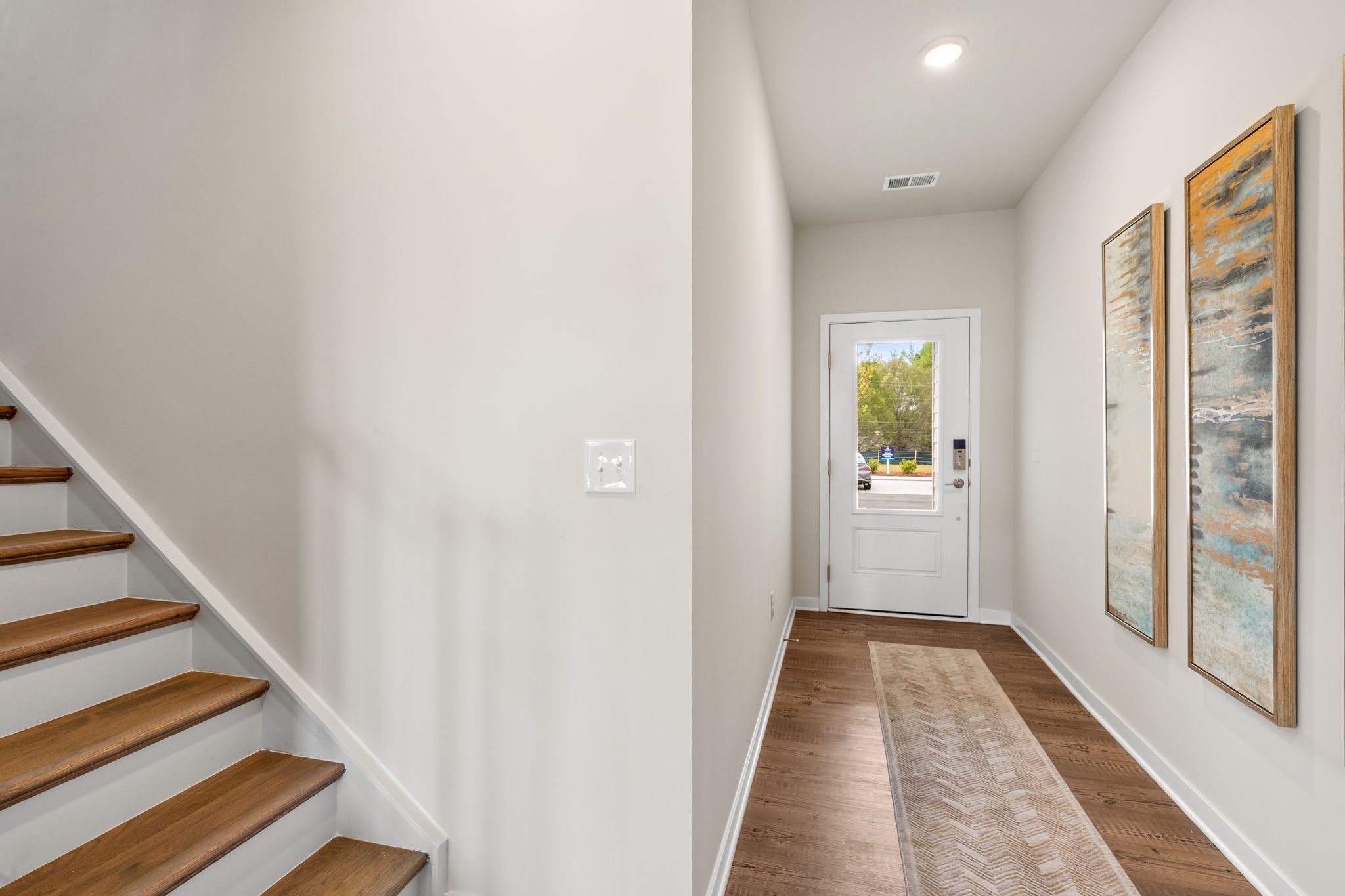A hallway with a door and a staircase.