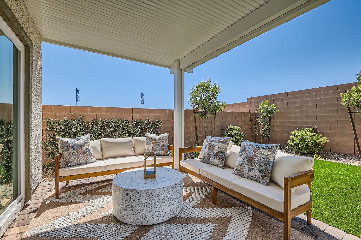 A patio with a couch and a table with a potted plant.