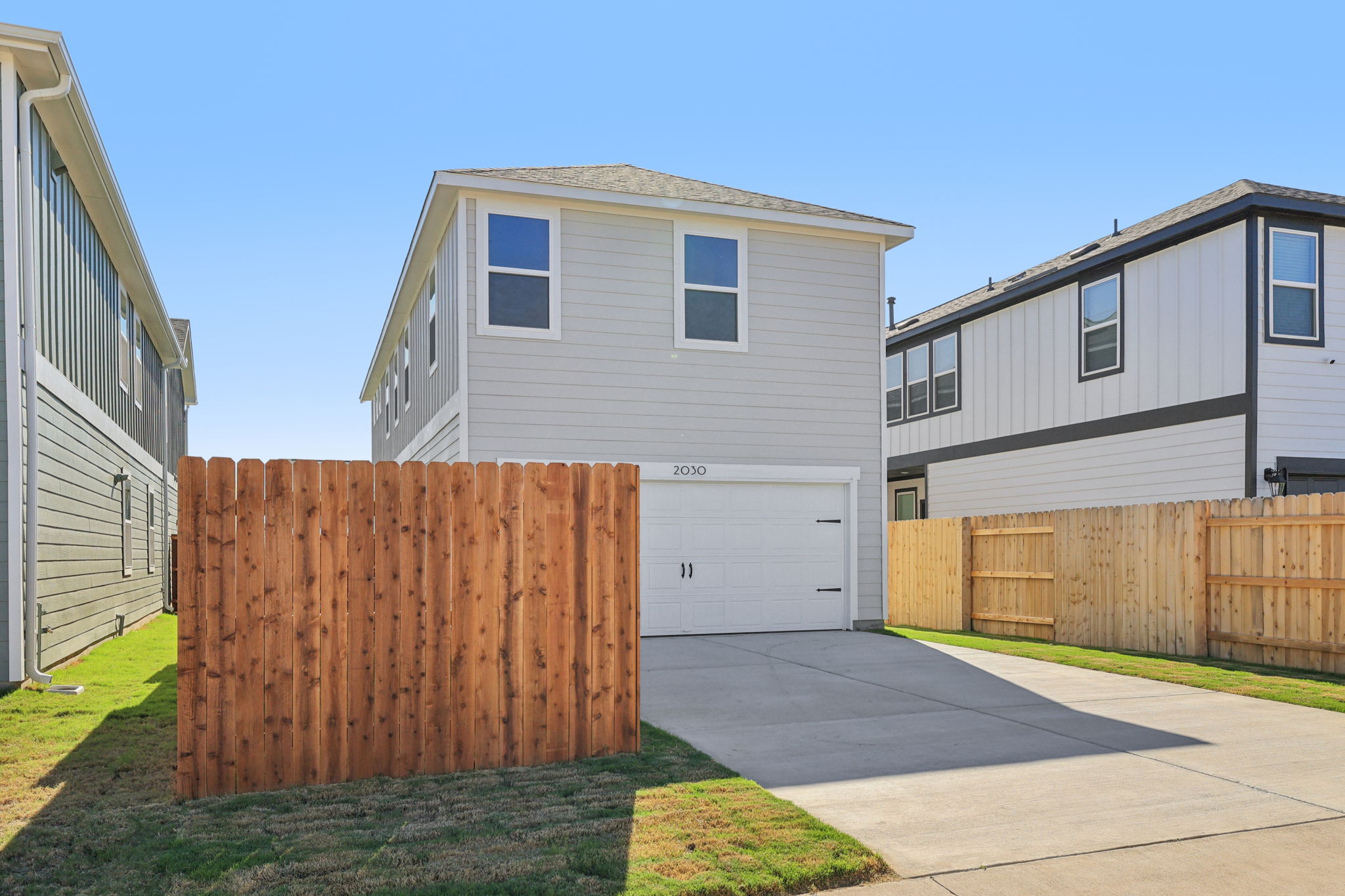 A fenced in yard with a wood gate and a house.