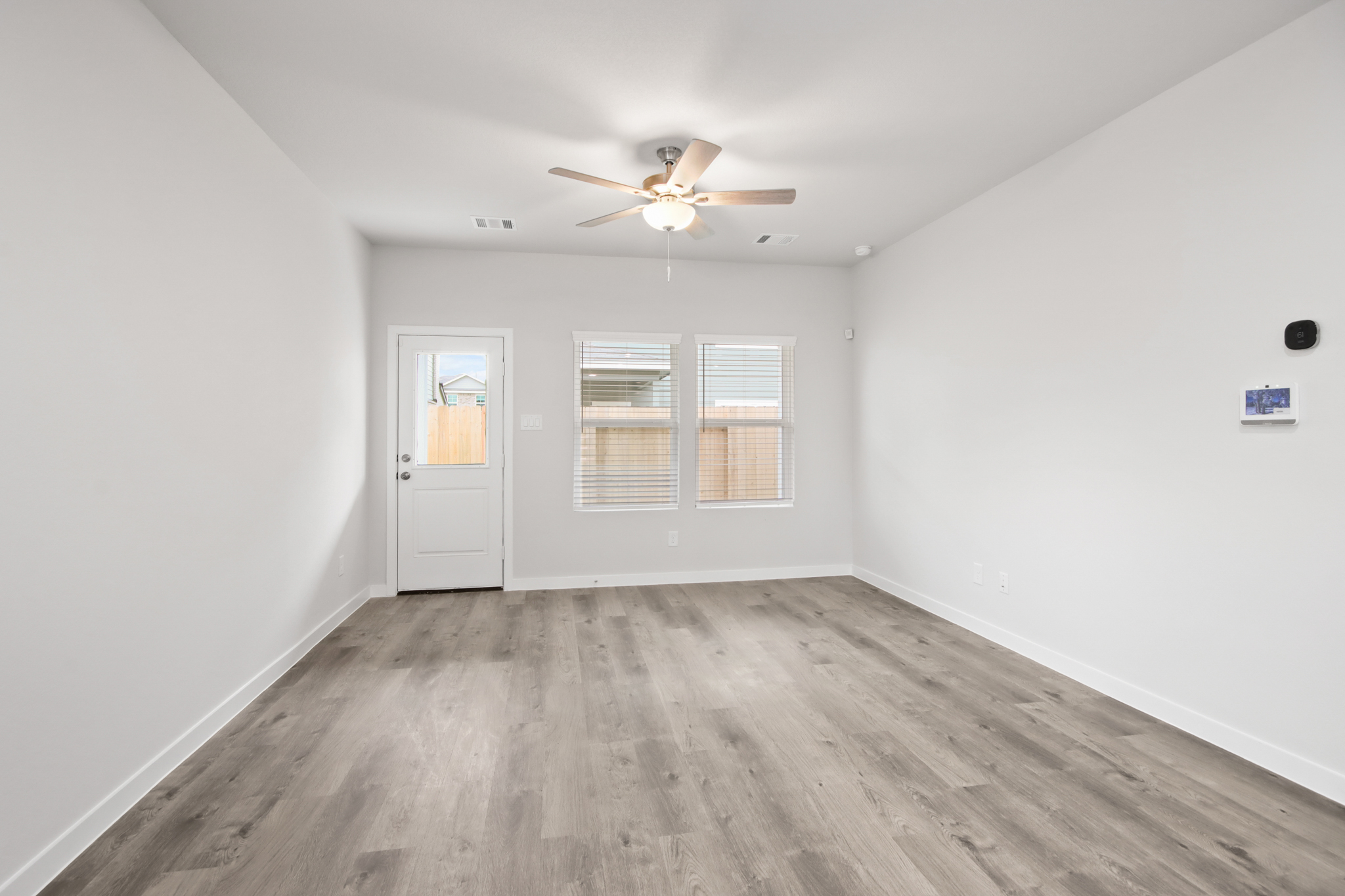 A room with a ceiling fan and a wood floor.