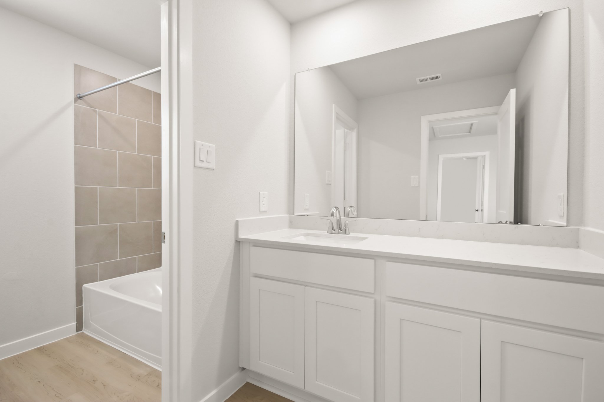 A bathroom with a tub sink and mirror.