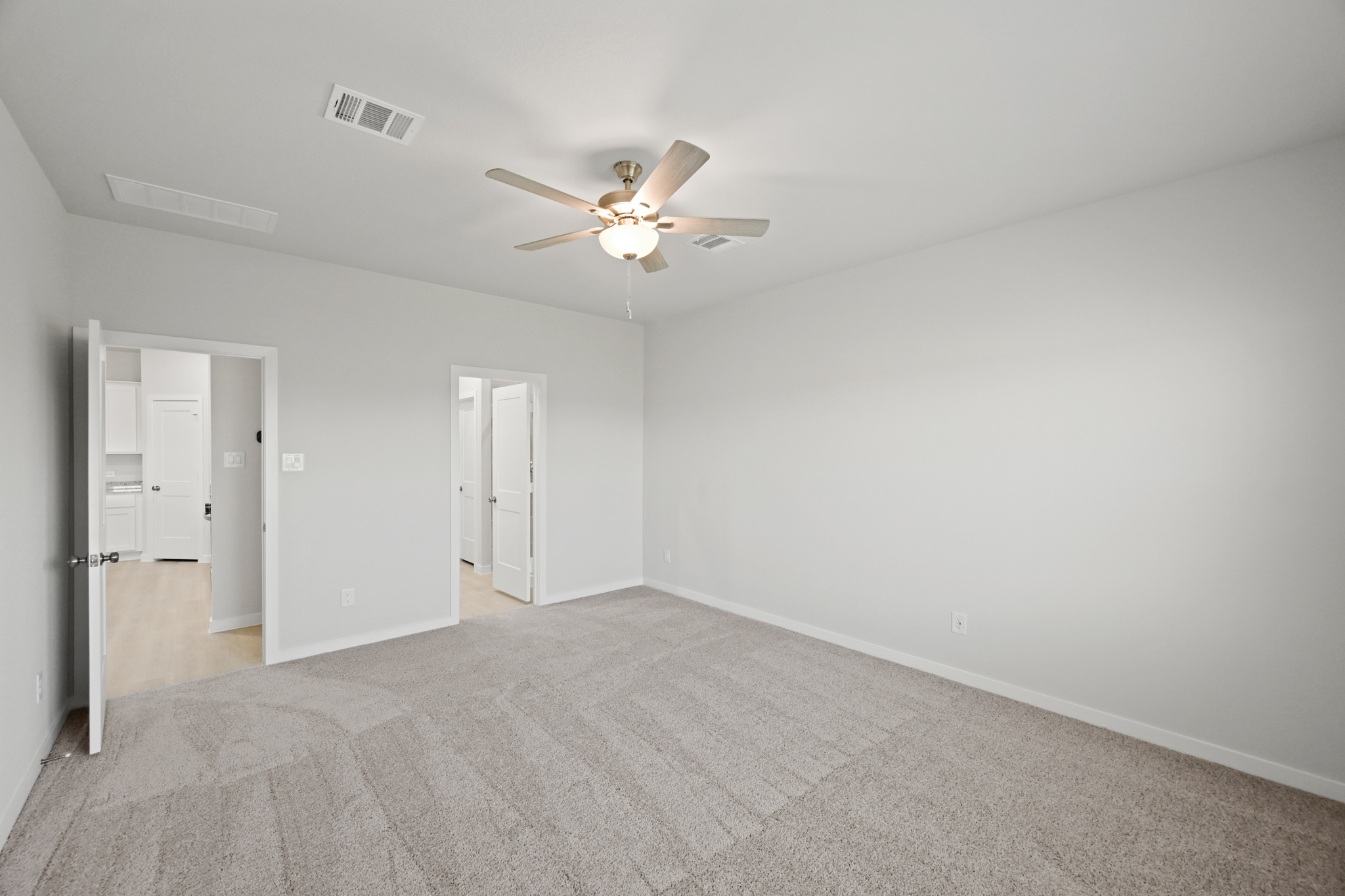 A room with a ceiling fan and white walls.