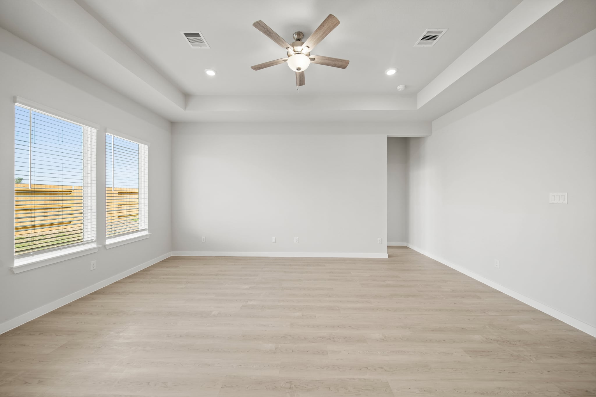 A room with a ceiling fan and a wood floor.