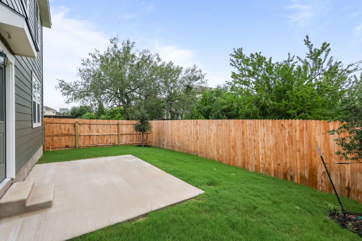 A backyard with a fence and trees.