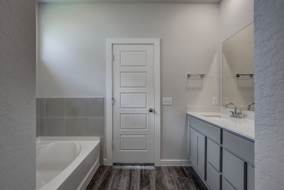 A bathroom with a tub sink and a mirror.