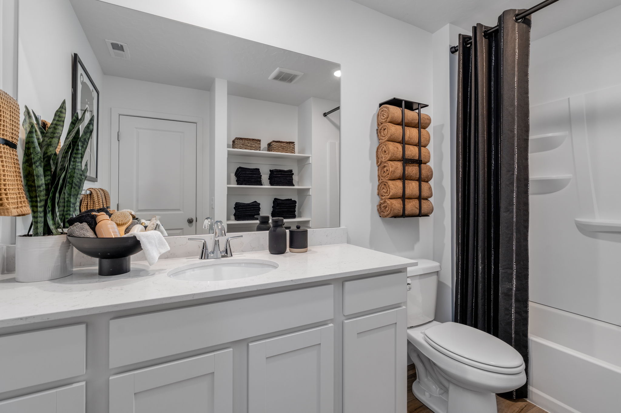 A bathroom with a sink toilet and shelves.