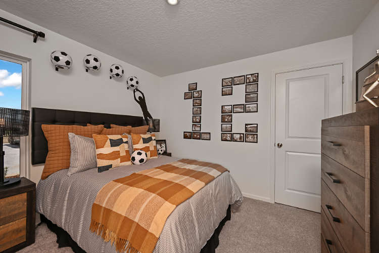 A bedroom with a bed and a wall with pictures on it.